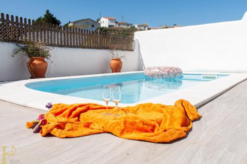 a table with two wine glasses and a blanket next to a swimming pool at Window to the Valley in Santo Isidoro