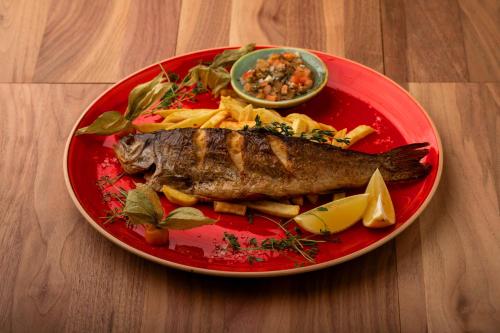 a red plate of food with a fish and pasta at An-Son Apartamenty in Zielona Góra