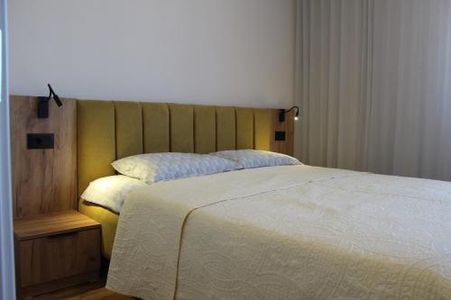 a bedroom with a large bed with a wooden headboard at Sun Apartments in Pristina