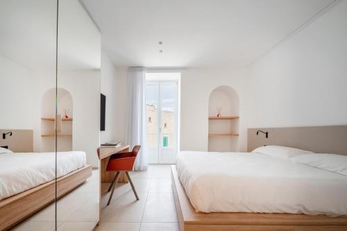 um quarto com duas camas, uma escrivaninha e um espelho em Porta San Biagio - rooms & apartments em Matera