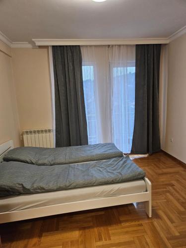 a bedroom with a bed in front of a window at Velike Šume Apartment in Pale