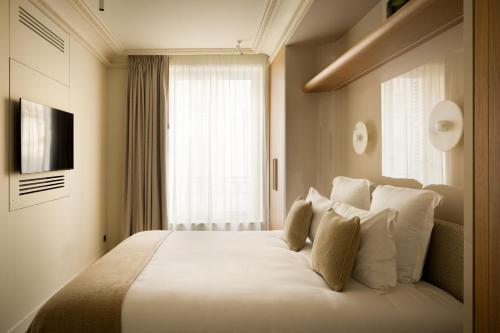 a bedroom with a large white bed with a window at HIGHSTAY Maisons - Boétie in Paris