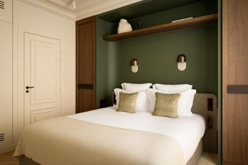 a bedroom with a white bed with a green wall at HIGHSTAY Maisons - Boétie in Paris