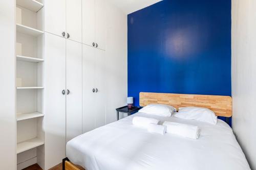 une chambre avec un lit blanc avec un mur bleu dans l'établissement GuestReady - Comfortable retreat in the 11th Arr, à Paris
