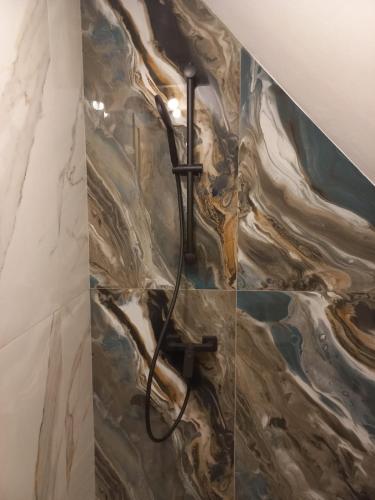 a shower in a bathroom with a marble wall at Căsuța bunicii in Cavnic