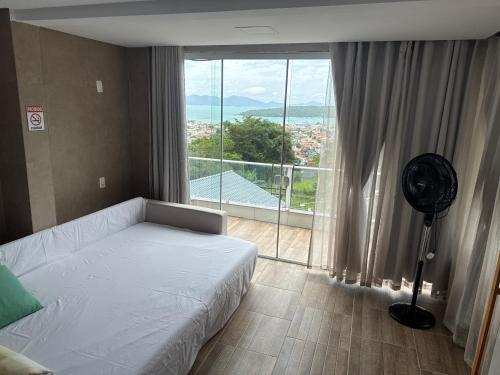 Un dormitorio con una cama y una ventana grande. en CASA COM PISCINA e VISTA PARA O MAR - Porto Belo-SC Bombinhas-SC, en Porto Belo