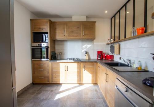 une cuisine avec des armoires en bois et des appareils en acier inoxydable dans l'établissement Chantegrel, à Auriac-du-Périgord