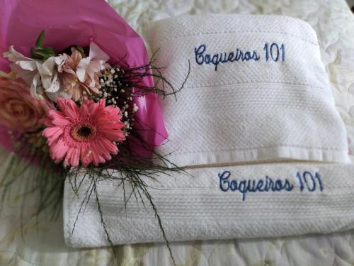 a white towel with a bouquet of flowers on it at Flat Coqueiros 101 Praia in Tamandaré