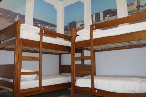 a group of bunk beds in a room with a window at Meeting Hostel in Figueira da Foz