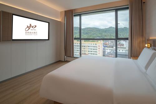 a hotel room with a white bed and a large window at Zhangjiajie Homeinn Plus Hotel in Zhangjiajie