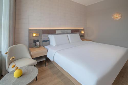 a bedroom with a large white bed and a chair at Zhangjiajie Homeinn Plus Hotel in Zhangjiajie