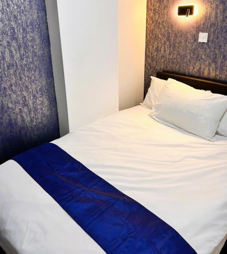 a bed with a white and blue blanket on it at Hillcrest Liverpool City Central in Liverpool