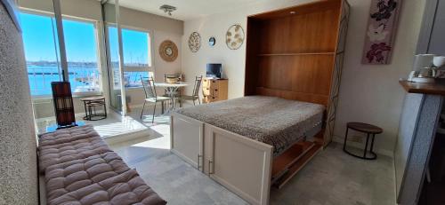 Cette chambre comprend un lit et une grande fenêtre. dans l'établissement GRAND STUDIO VUE PANORAMIQUE SUR LE PORT, PARKING PRIVE, au Cap d'Agde