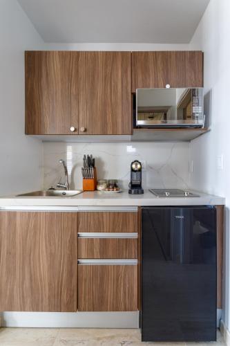 a kitchen with wooden cabinets and a black dishwasher at Placencia Resort in Maya Beach