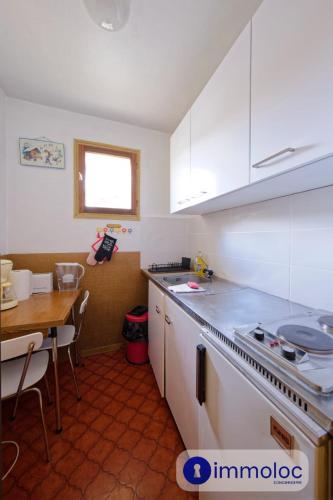 une cuisine avec des placards blancs, une table et un comptoir dans l'établissement Apartment in Auron 100 meters from the slopes, à Auron