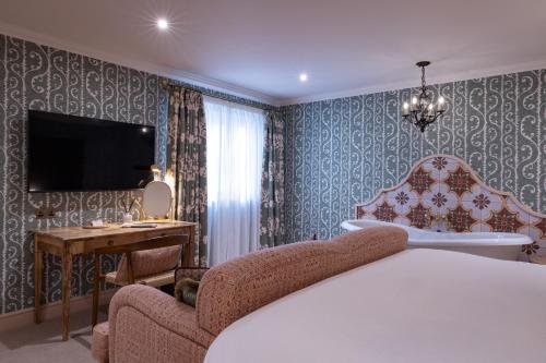a bedroom with a bed and a tv and a chair at The White Hart - A Heartwood Inn in Lewes