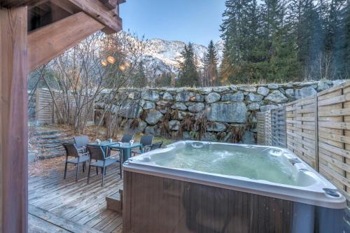 - un bain à remous sur une terrasse avec une table et des chaises dans l'établissement Chalet Hideaway 2 - Welkeys, à Chamonix-Mont-Blanc
