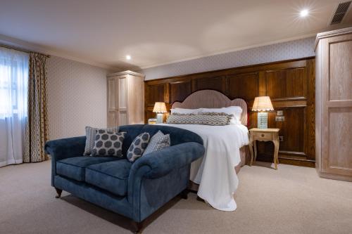 a bedroom with a large bed and a blue couch at The White Hart - A Heartwood Inn in Lewes