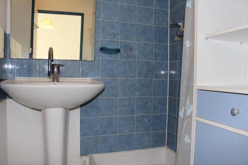 La salle de bains est pourvue de carrelage bleu, d'un lavabo et d'un miroir. dans l'établissement SP280-1142 Appartement 2 pièces - mezzanine SAINT PIERRE LA MER, à Saint Pierre La Mer