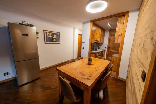 a kitchen with a wooden table and a refrigerator at Appartamento Prestige in Sestriere