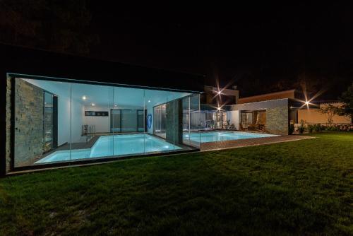 a large glass house with a swimming pool at night at Lux Villa with heated indoor Pool at Aroeira Sea & Golf Resort - Lisbon in Almada