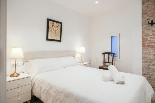 a white bedroom with two beds and a chair at Ganganell Àtic Apartamento con terraza en Besalú in Besalú