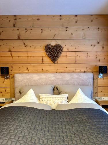 a bed with a heart on a wooden wall at Landhaus Knaus in Leutasch