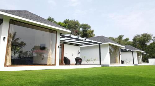 a house with large windows and a green lawn at The Winterfell Premium Homestay By Dazzle Destinations in Somvārpet