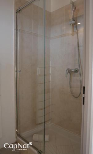 une douche avec une porte vitrée dans une salle de bain dans l'établissement CapNat - Village Naturiste - Heliopolis - Appartement 2 pieces - Le Mont Olympe, au Cap d'Agde