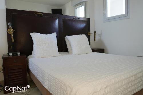 une chambre avec un grand lit avec des draps et des oreillers blancs dans l'établissement CapNat - Village Naturiste - Heliopolis - Appartement 2 pieces - Le Mont Olympe, au Cap d'Agde