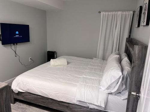 een slaapkamer met een bed met witte lakens en een televisie bij Exclusive Spacious 2 Kings Bed by EWR NYC in Newark