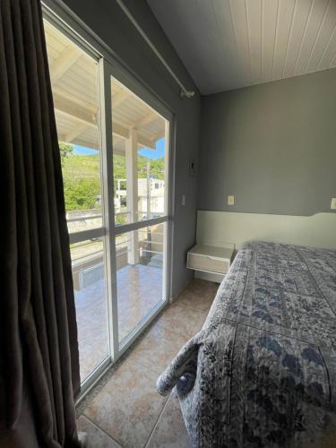 Un dormitorio con una cama y una ventana grande. en Casa no centro de Porto Belo, en Porto Belo