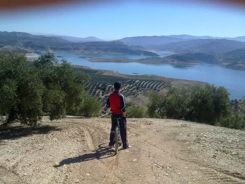a man on a bike on a hill overlooking a lake at El Rincon de Carmen in Rute