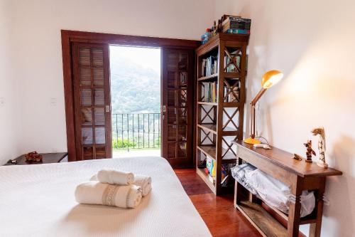 a bedroom with a bed and a desk and a window at Refúgio na Serra - Casa 3 suítes em Condomínio in Pedro do Rio