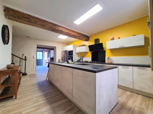 une cuisine avec des murs jaunes et un grand comptoir dans l'établissement Maison Familiale du Quercy, à Montpezat-de-Quercy