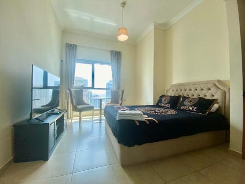 a bedroom with a bed with a television and a balcony at Cosy Studio in Marina in Dubai