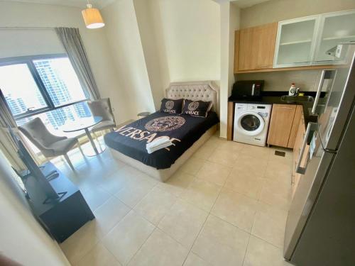 a small bedroom with a bed and a kitchen at Cosy Studio in Marina in Dubai