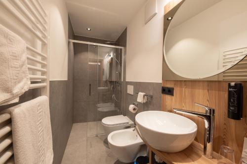a bathroom with a sink and a toilet and a mirror at Hotel Mondschein in Sesto