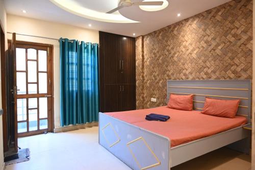 a bedroom with a bed with orange sheets and a ceiling at Castle Inn Oasis Homestay in Dehradun