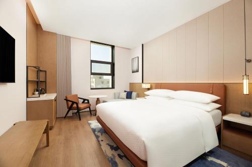 敦煌市にあるFour Points by Sheraton Dunhuangの大きな白いベッドと机のある寝室