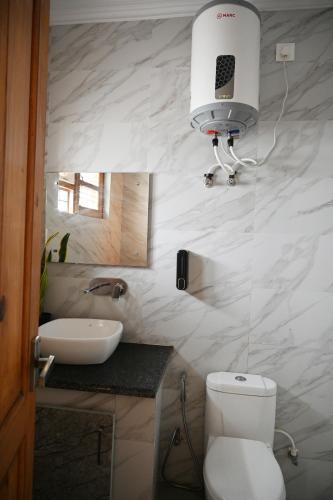 a bathroom with a toilet and a light on the wall at Castle Inn Oasis Homestay in Dehradun