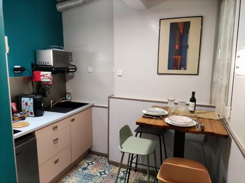 une petite cuisine avec une table, des chaises et un évier dans l'établissement Confortable près des transports, à Paris