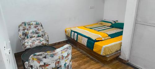 a small bedroom with a bed and a chair at The White House Farms in New Delhi
