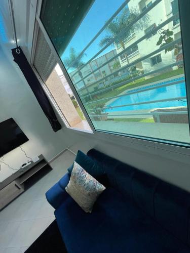 a living room with a blue couch and a large window at Sable d'or in El Harhoura