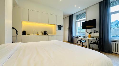 a white bedroom with a white bed and a desk at Studio Fischer à la Pétrusse 002 in Luxembourg
