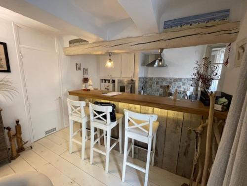 une cuisine avec un bar et des tabourets blancs dans l'établissement appartement loft dans la Vieille Ville, à Sainte-Maxime