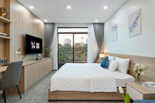 a bedroom with a bed and a desk and a television at 22Land Cosmos Hotel in Hanoi
