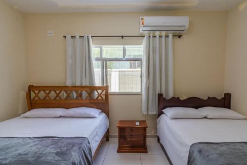 a bedroom with two beds and a window with a heater at Casa com piscina e churrasqueira na Praia Seca in Araruama