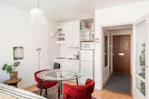 une petite cuisine avec une table en verre et deux chaises rouges dans l'établissement Central and Hip w King Bed, 50m tram and bus, Netflix, à Helsinki