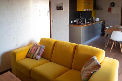 a yellow couch in a living room with a kitchen at Ecofurtado in Furtado